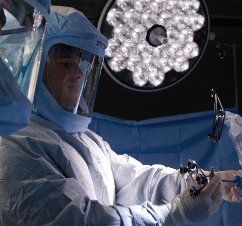 Adam Stillo holding medical equipment in operating room