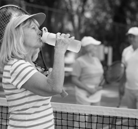 Woman drinking water on tennis court