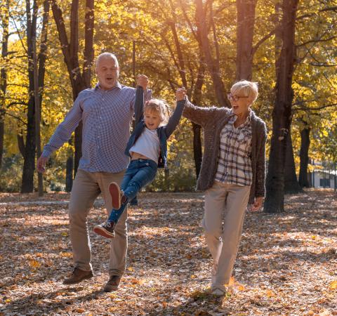 Grandparents playing with granddaughter in the park